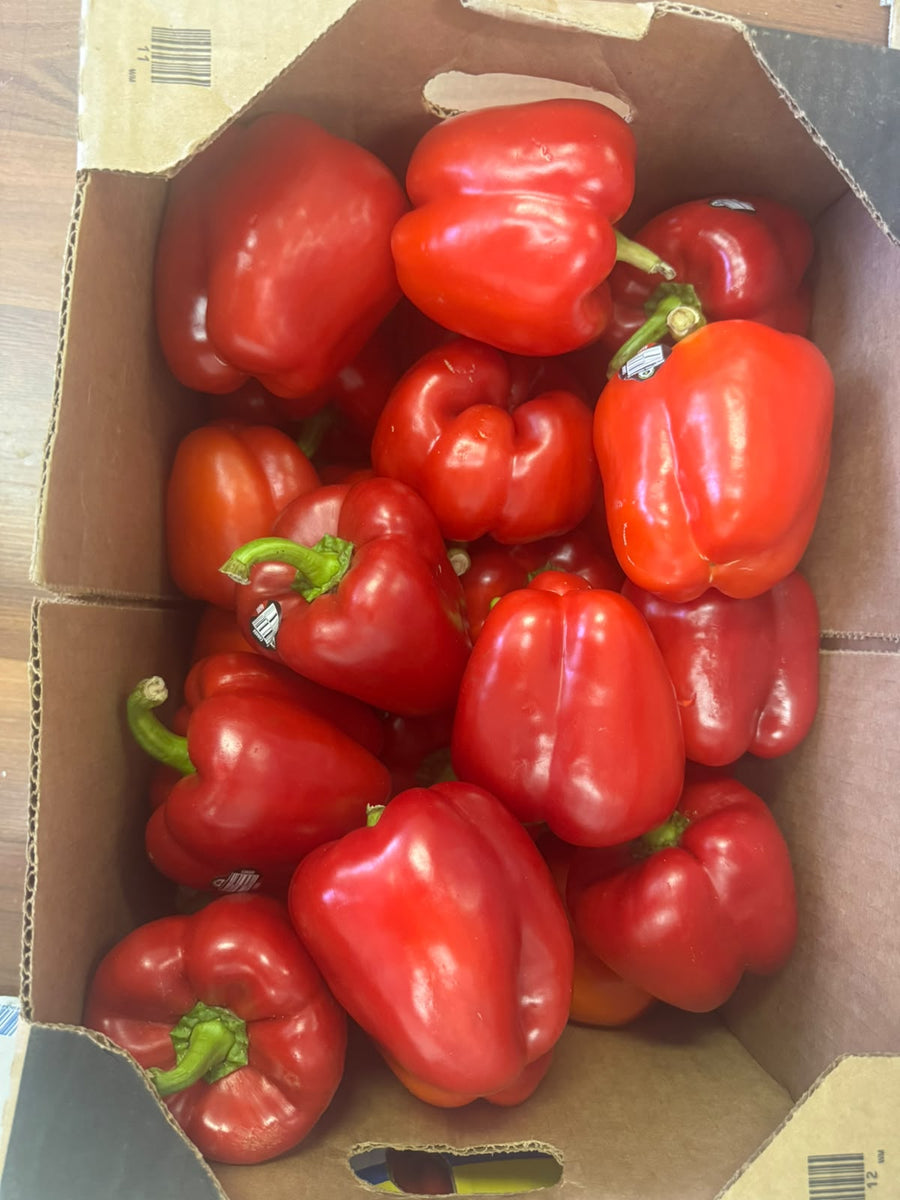 Fresh red bell peppers in a cardboard box